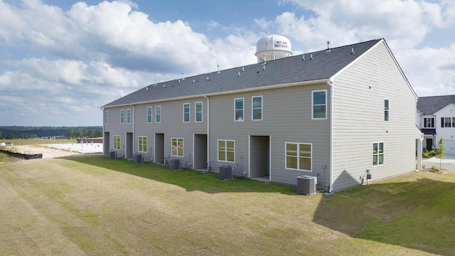 rear view of property with central AC and a lawn