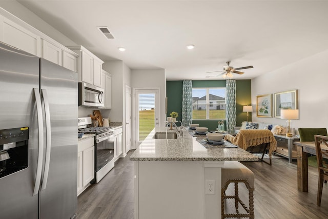 kitchen with sink, white cabinetry, stainless steel appliances, and a kitchen island with sink