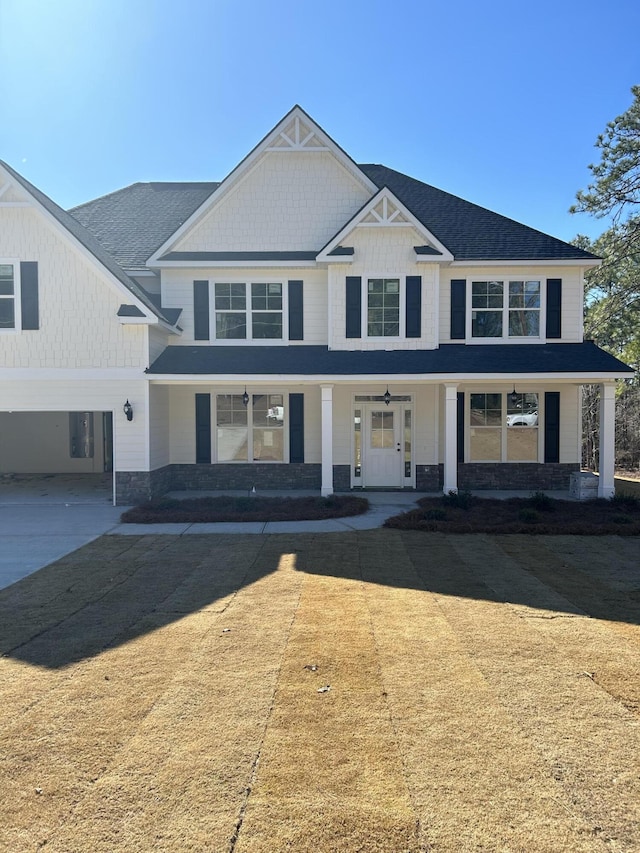 view of front of home featuring covered porch, a garage, and a front lawn