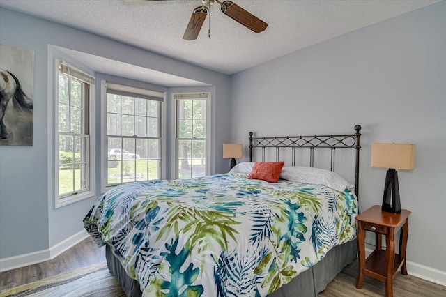 bedroom with ceiling fan, hardwood / wood-style floors, and a textured ceiling