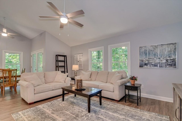 living room with wood-type flooring, lofted ceiling, a healthy amount of sunlight, and ceiling fan