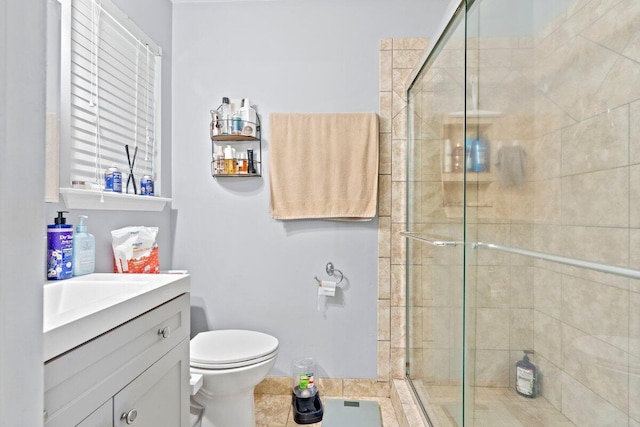 bathroom featuring tile patterned floors, vanity, toilet, and a shower with shower door