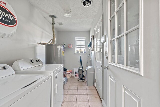 laundry room featuring light tile patterned flooring, gas water heater, a textured ceiling, and washing machine and dryer