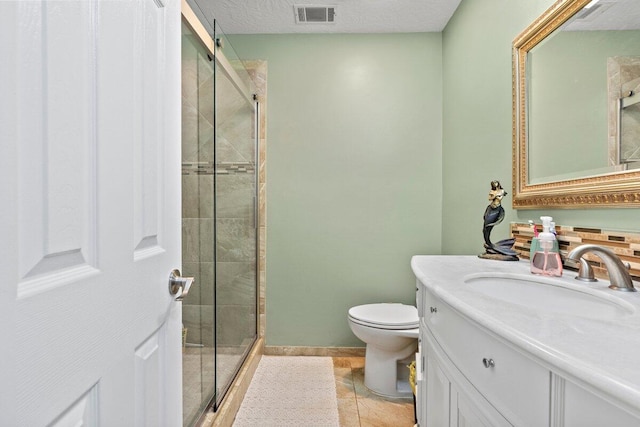 bathroom featuring vanity, tile patterned flooring, toilet, a textured ceiling, and a shower with shower door