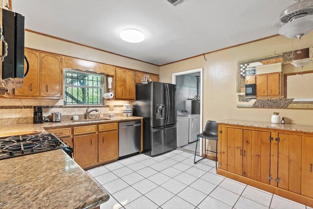 kitchen with washing machine and clothes dryer, sink, stainless steel appliances, decorative backsplash, and ornamental molding