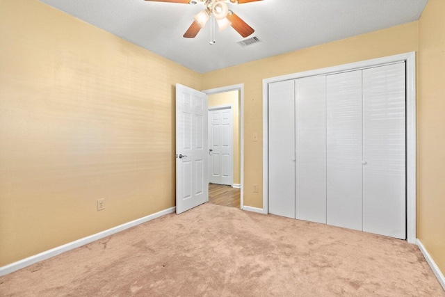 unfurnished bedroom with ceiling fan, light colored carpet, and a closet