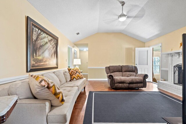 living room featuring ceiling fan, dark parquet floors, a textured ceiling, vaulted ceiling, and a fireplace