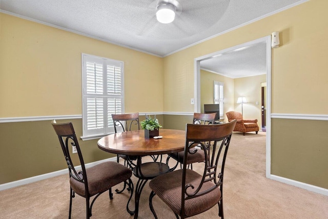 dining area with a textured ceiling, ceiling fan, crown molding, and light carpet