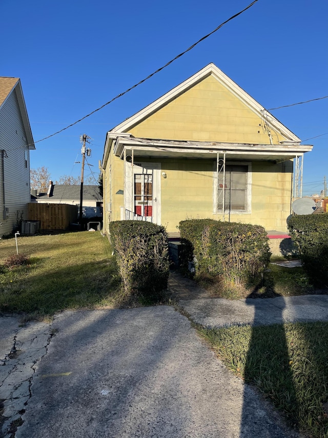 bungalow-style house with a front yard and central AC unit