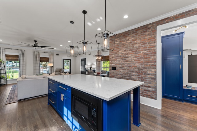 kitchen featuring blue cabinetry, black microwave, a kitchen island, pendant lighting, and brick wall