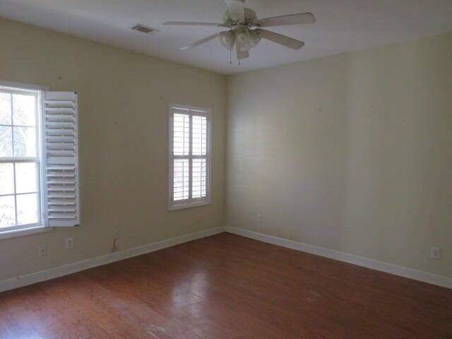 empty room featuring dark hardwood / wood-style floors, a wealth of natural light, and ceiling fan