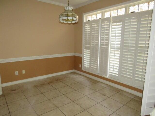 spare room featuring crown molding and light tile patterned floors