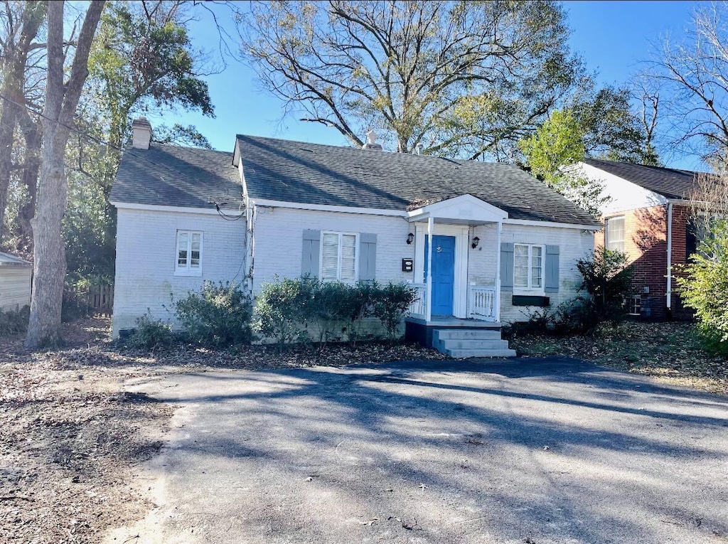 view of front of home with brick siding, a chimney, and roof with shingles