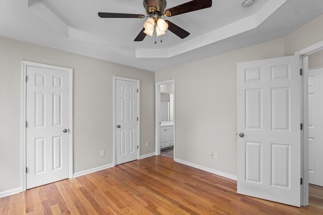 603 Ridgefield Dr, North Augusta, SC 29841 - unfurnished bedroom featuring a tray ceiling, multiple closets, light wood-style floors, and connected bathroom