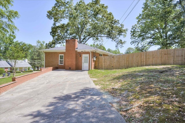view of front of home with brick siding, fence, and a chimney