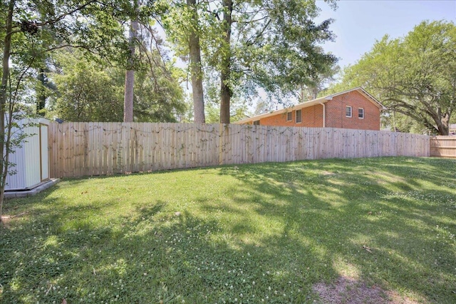 view of yard with a fenced backyard, a shed, and an outbuilding