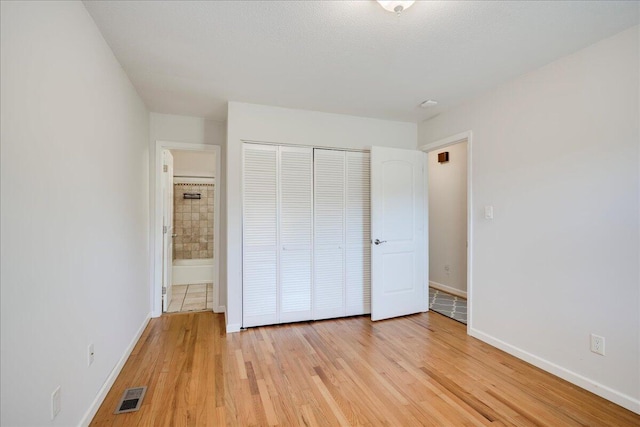 unfurnished bedroom featuring visible vents, baseboards, a closet, and light wood-type flooring