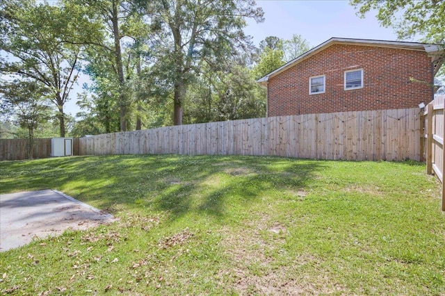 view of yard with an outdoor structure, a fenced backyard, and a shed