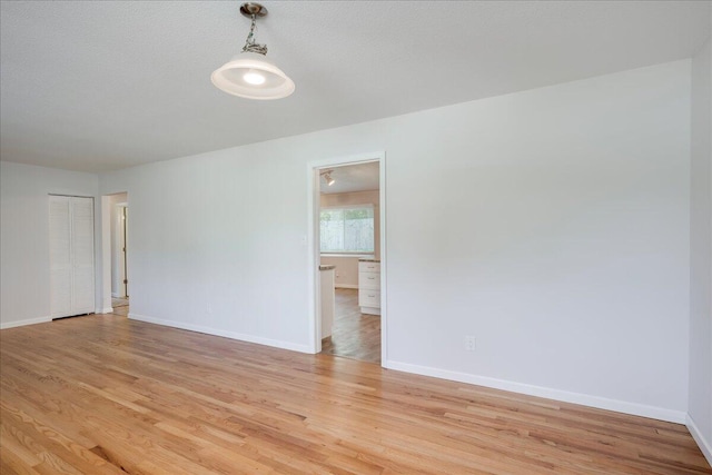 unfurnished room featuring baseboards and light wood-type flooring