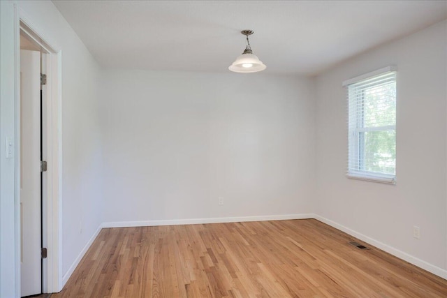 spare room with baseboards, light wood-style flooring, and visible vents