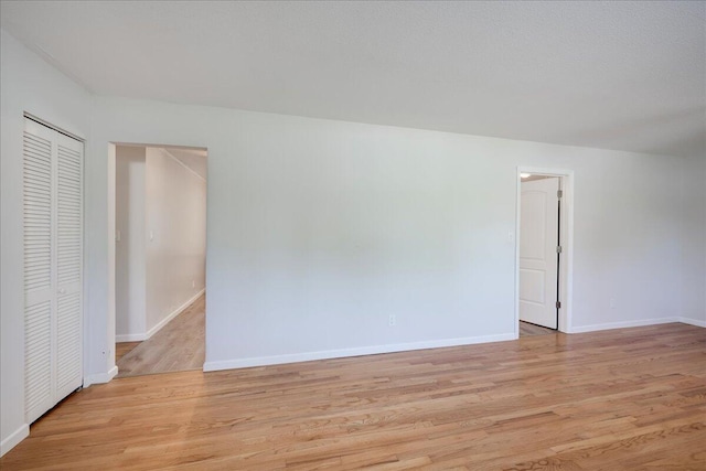 spare room featuring baseboards and light wood-type flooring