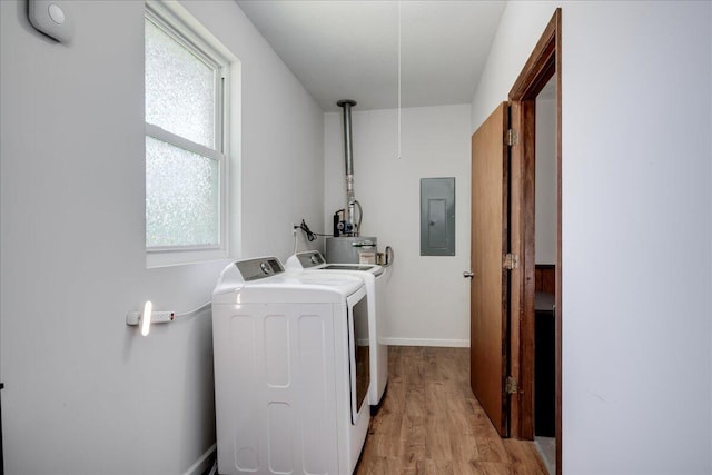 laundry room with laundry area, light wood-style floors, baseboards, electric panel, and washing machine and clothes dryer