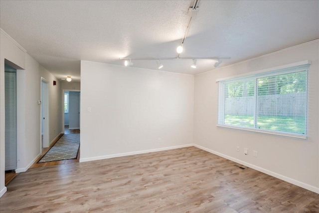 spare room featuring visible vents, track lighting, wood finished floors, baseboards, and a textured ceiling