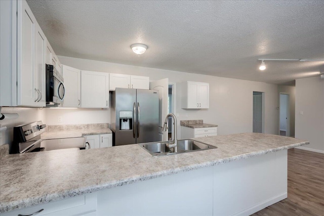 kitchen with appliances with stainless steel finishes, a sink, light countertops, a textured ceiling, and dark wood finished floors