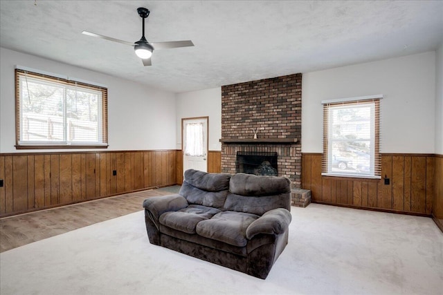 living room featuring wooden walls, ceiling fan, and wainscoting