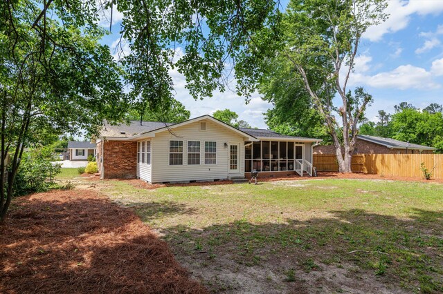 rear view of house featuring a lawn, fence, a sunroom, and crawl space