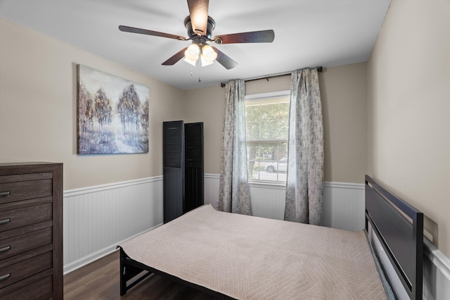 bedroom featuring wood finished floors, a wainscoted wall, and ceiling fan