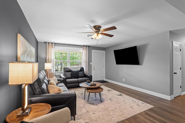 living area featuring dark wood-style flooring, a ceiling fan, and baseboards