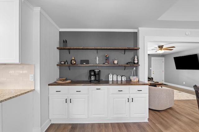 bar featuring wood finished floors, ceiling fan, decorative backsplash, and baseboards