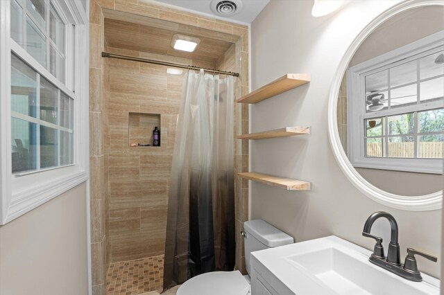 full bath with toilet, visible vents, tiled shower, and vanity