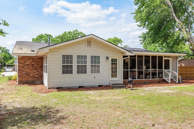 rear view of house featuring entry steps, crawl space, fence, a yard, and a sunroom
