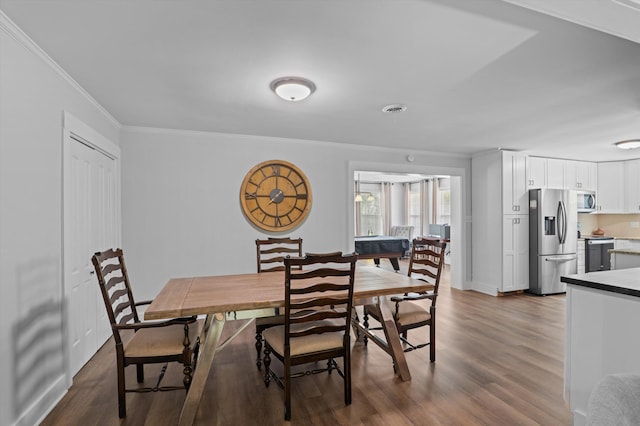 dining room featuring dark wood finished floors, baseboards, and crown molding