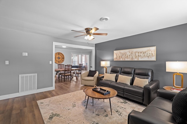 living area with visible vents, ceiling fan, wood finished floors, and baseboards