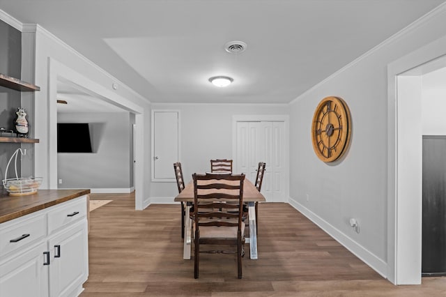dining area featuring ornamental molding, wood finished floors, and baseboards