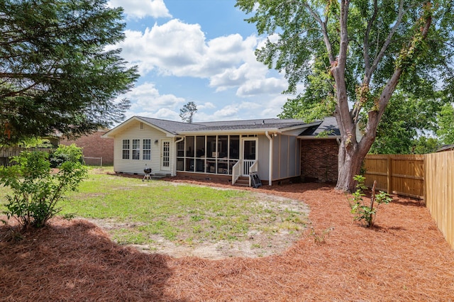 rear view of property with a fenced backyard, a yard, and a sunroom