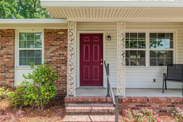 property entrance with a porch and brick siding