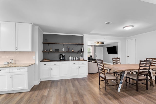 dining room with wood finished floors, a ceiling fan, visible vents, and baseboards