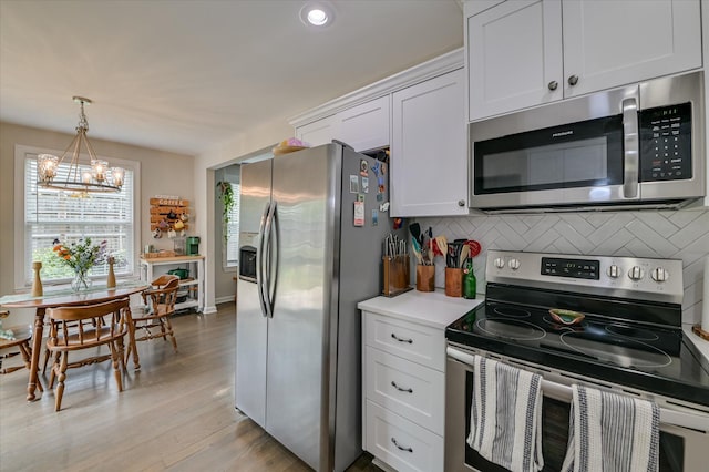1745 Oak Dr, Augusta, GA 30904 - kitchen with stainless steel appliances, a chandelier, backsplash, light wood-style flooring, and white cabinetry