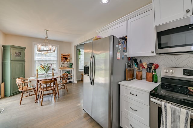 1745 Oak Dr, Augusta, GA 30904 - kitchen with appliances with stainless steel finishes, tasteful backsplash, a chandelier, light wood finished floors, and light countertops