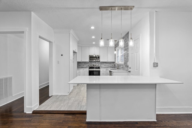 kitchen featuring backsplash, white cabinets, sink, decorative light fixtures, and stainless steel appliances