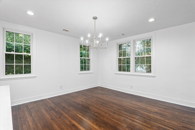 unfurnished room featuring a notable chandelier, dark hardwood / wood-style flooring, and a textured ceiling