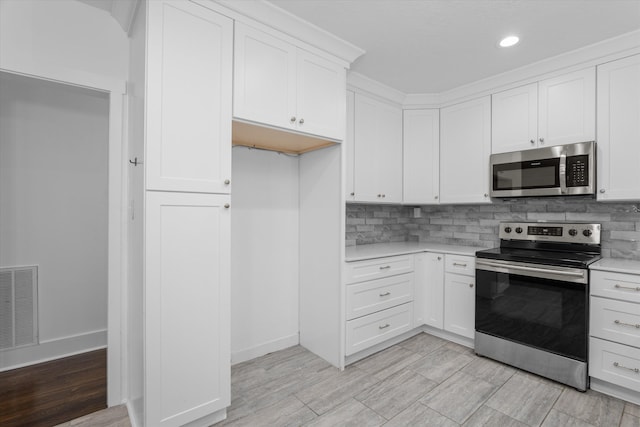 kitchen featuring backsplash, stainless steel appliances, and white cabinetry