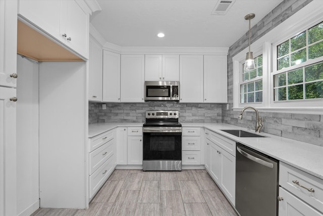 kitchen with decorative backsplash, stainless steel appliances, sink, pendant lighting, and white cabinetry