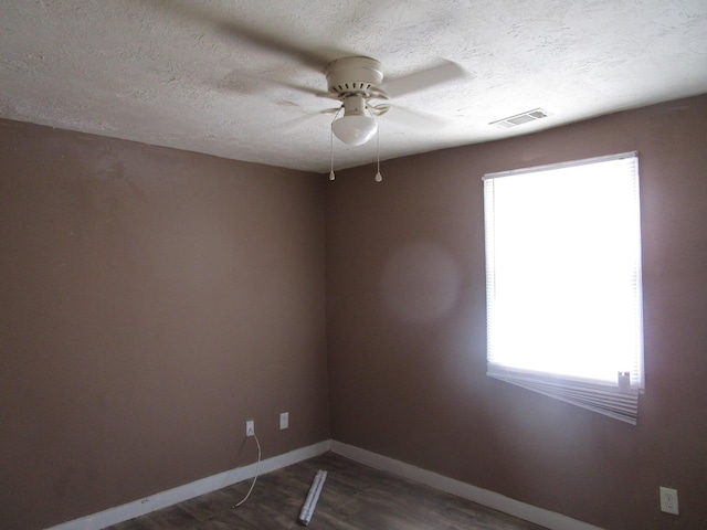 spare room with a healthy amount of sunlight, a textured ceiling, ceiling fan, and dark wood-type flooring