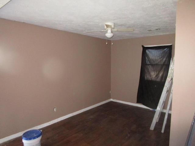 spare room featuring dark hardwood / wood-style floors, ceiling fan, and a textured ceiling