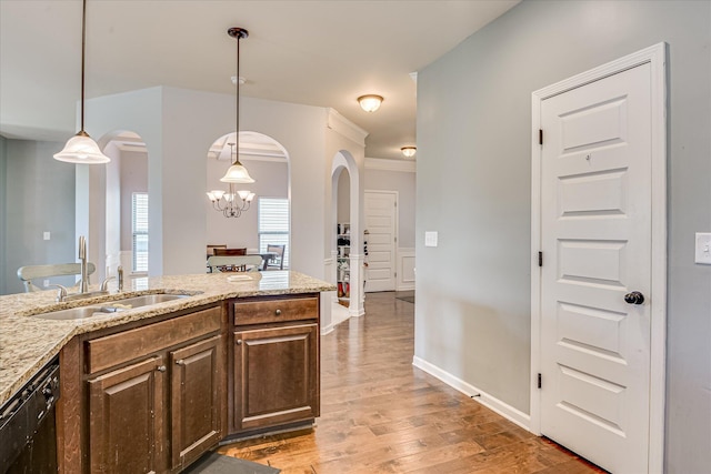 3374 Grove Landing Cir, Grovetown, GA 30813 - kitchen with arched walkways, a sink, light wood-style floors, light stone counters, and hanging light fixtures